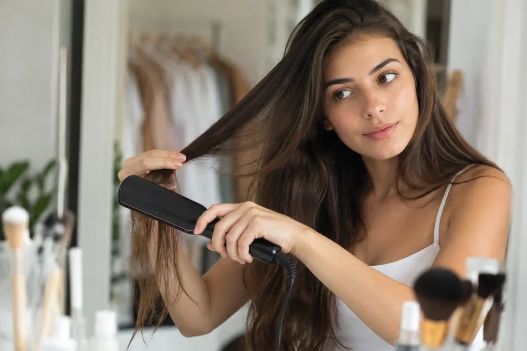 Woman styling long hair with a heated brush to reduce frizz and create smoother hair.